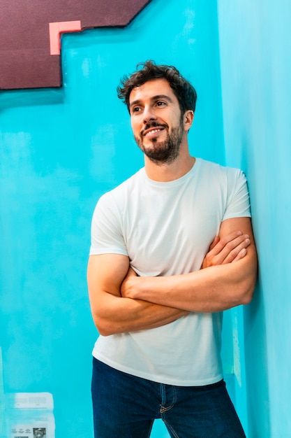 Un jeune homme de race blanche souriant dans un t-shirt blanc et une veste en jean