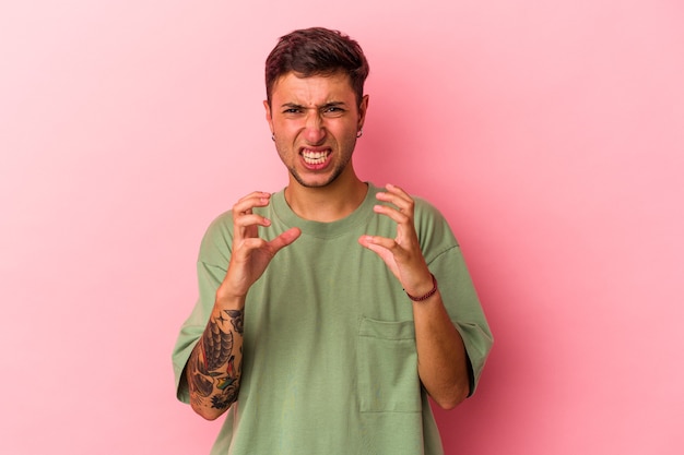 Jeune homme de race blanche avec des tatouages isolés sur fond jaune contrarié en criant avec des mains tendues.