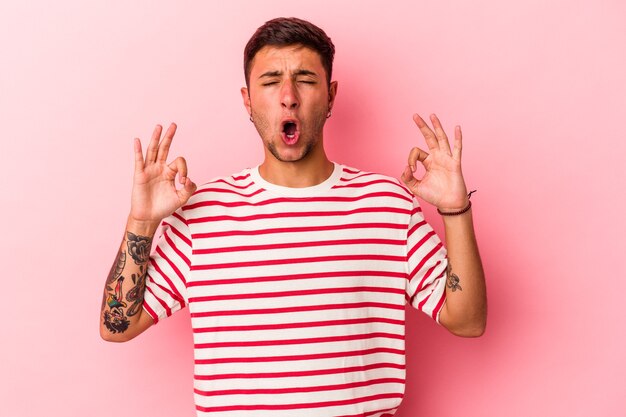 Jeune homme de race blanche avec des tatouages isolés sur fond jaune se détend après une dure journée de travail, elle fait du yoga.