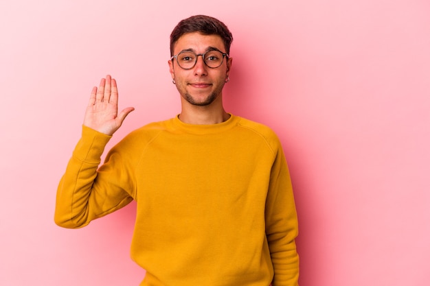 Jeune homme de race blanche avec des tatouages isolés sur fond jaune souriant joyeux montrant le numéro cinq avec les doigts.