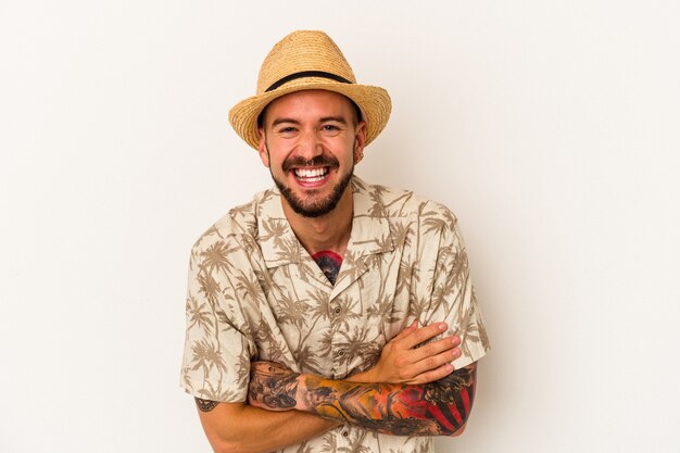 Jeune homme de race blanche avec des tatouages portant des vêtements d'été isolés sur fond blanc en riant et en s'amusant.