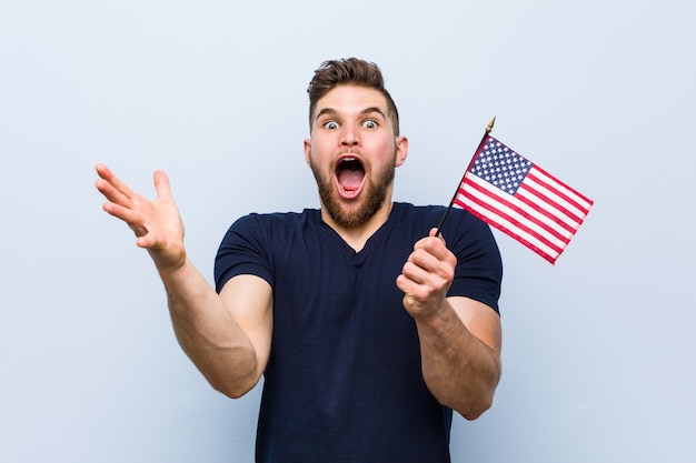 Jeune homme de race blanche tenant un drapeau des États-Unis célébrant une victoire ou un succès