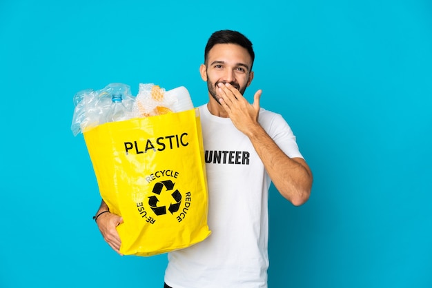 Jeune homme de race blanche tenant un sac plein de bouteilles en plastique à recycler isolé