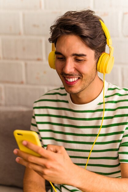 Jeune homme de race mixte écoutant de la musique assis sur le canapé