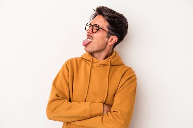 Jeune homme de race mixte isolé sur fond blanc drôle et sympathique qui sort la langue.