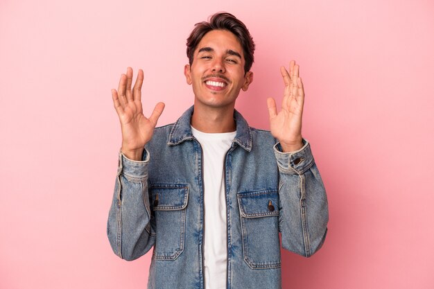 Jeune homme de race mixte isolé sur fond blanc éclate de rire en gardant la main sur la poitrine.