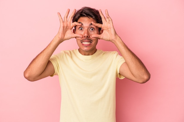 Jeune homme de race mixte isolé sur fond blanc en gardant les yeux ouverts pour trouver une opportunité de réussite.