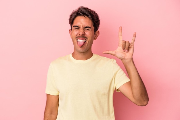 Jeune homme de race mixte isolé sur fond blanc montrant rock geste avec les doigts