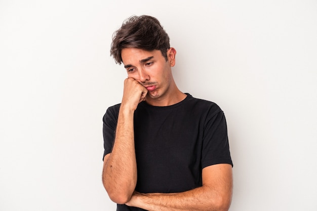 Jeune homme de race mixte isolé sur fond blanc qui se sent triste et pensif, regardant l'espace de copie.