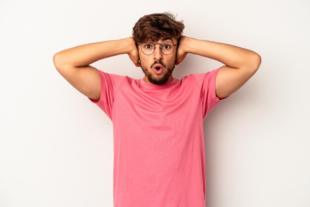 Jeune homme de race mixte isolé sur fond gris couvrant les oreilles avec les mains essayant de ne pas entendre un son trop fort.