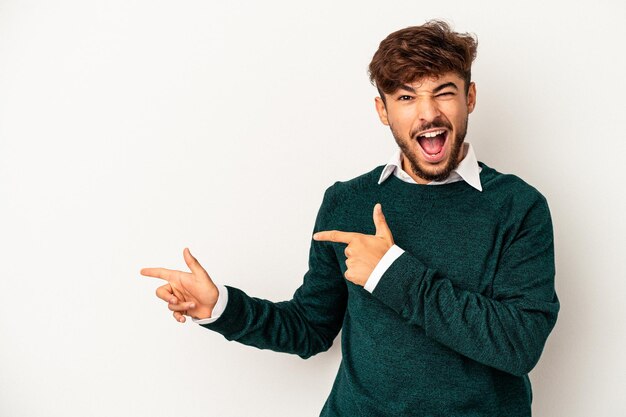 Jeune homme de race mixte isolé sur fond gris pointant avec les index vers un espace de copie, exprimant l'excitation et le désir.