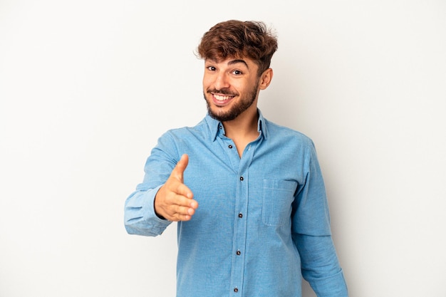 Jeune homme de race mixte isolé sur fond gris s'étendant la main à la caméra en geste de salutation.