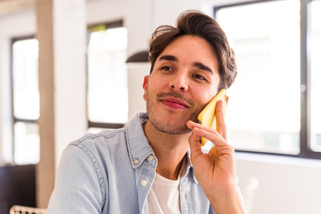 Jeune homme de race mixte parlant au téléphone dans une cuisine