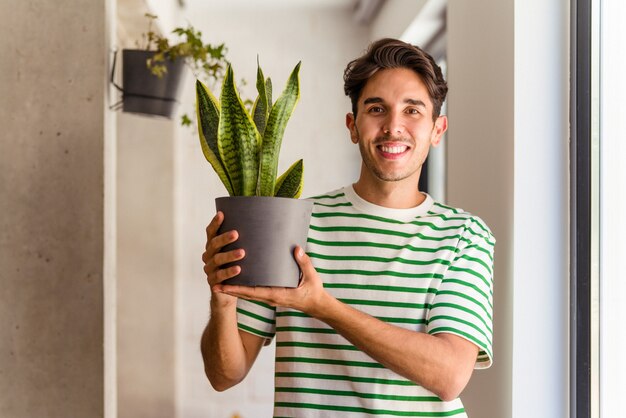 Jeune homme de race mixte avec une plante dans sa maison