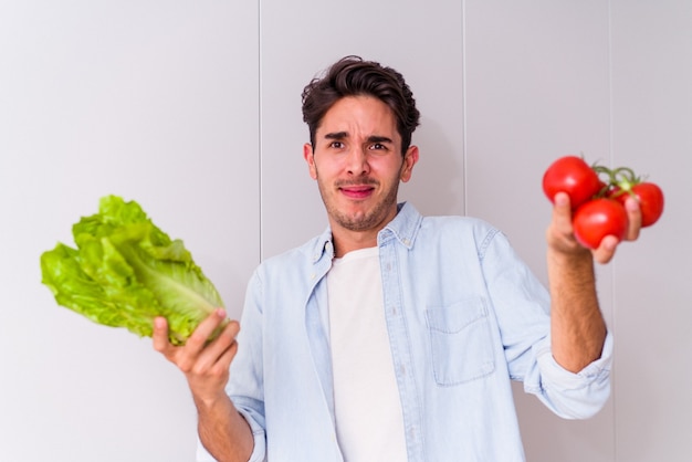 Jeune homme de race mixte préparant une salade pour le déjeuner