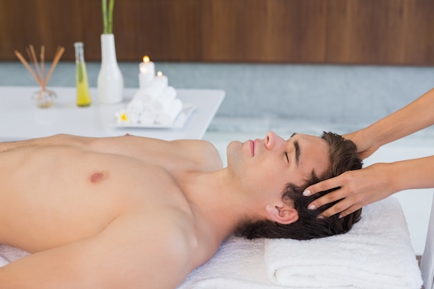 Jeune homme recevant un massage de la tête au centre de spa