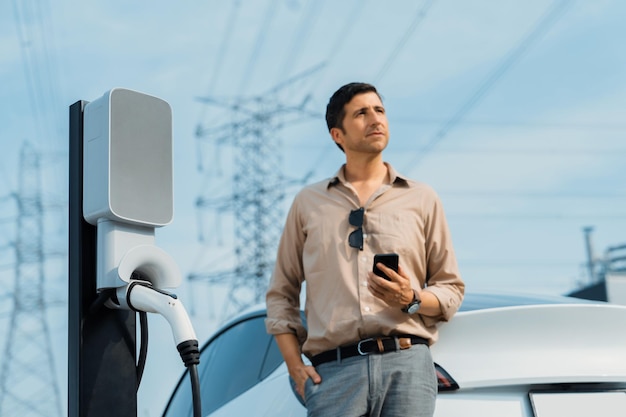 Un jeune homme recharge la batterie de sa voiture à une station de recharge.