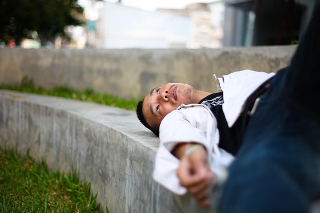 Un jeune homme réfléchi allongé sur un mur de soutènement