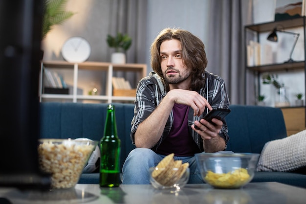 Jeune homme regardant un programme sportif à la télévision