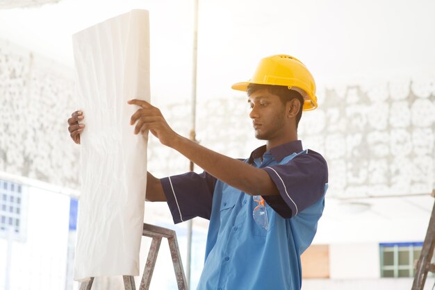 Photo un jeune homme regarde un plan alors qu'il se tient sur un chantier de construction