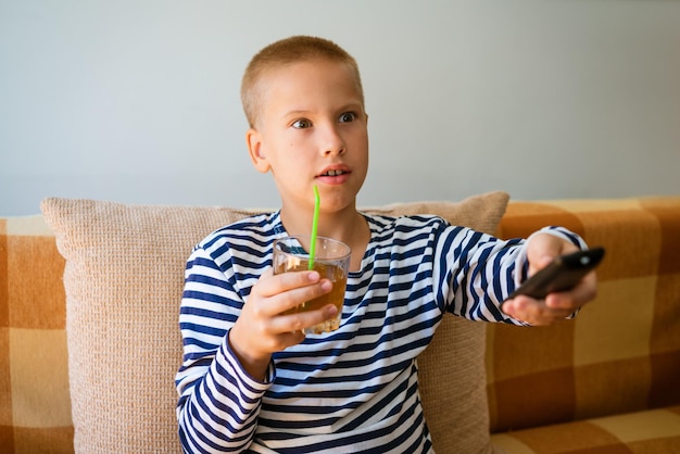 Un jeune homme regarde la télévision en utilisant la télécommande pour changer de chaîne. Le gars s'est ennuyé.