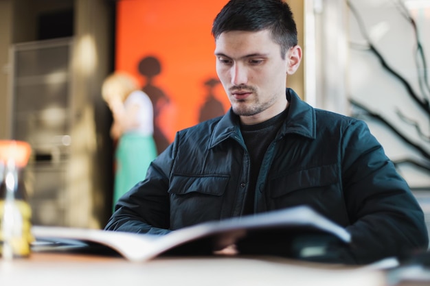 Un jeune homme regarde à travers un menu de livre dans un restaurant