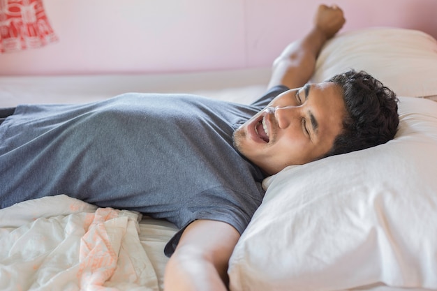 Jeune homme relaxant sur le lit