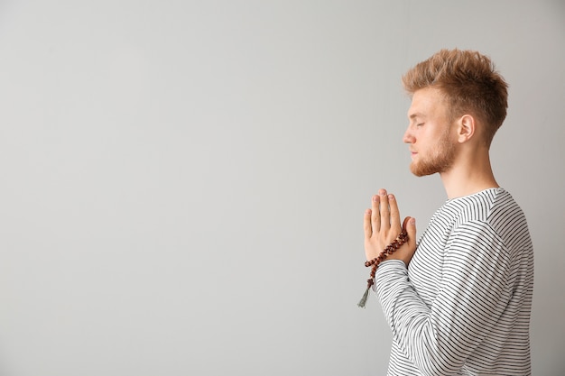 Jeune homme religieux priant Dieu sur gris