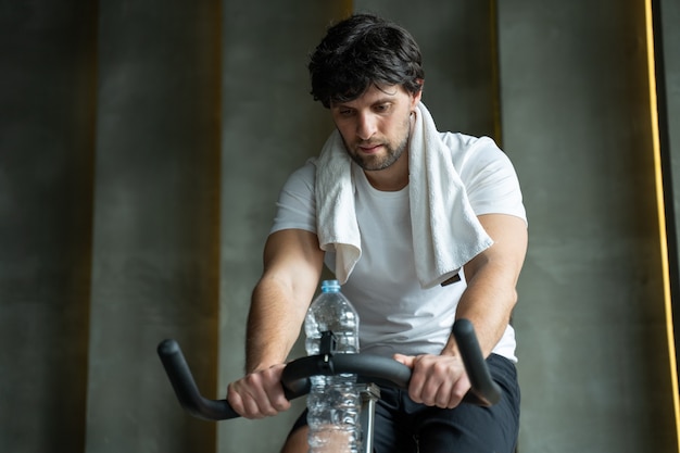 Jeune homme de remise en forme exerçant ses jambes cardio training sur vélo dans la salle de gym homme travaillant sur des vélos en rotation dans la salle de sport