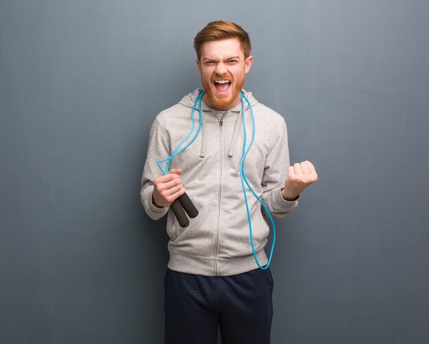 Jeune homme de remise en forme rousse surpris et choqué. Il tient une corde à sauter.