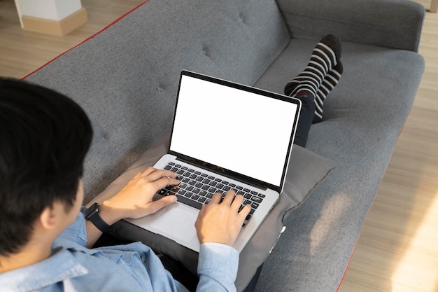 Jeune homme reposant sur un canapé confortable et naviguant sur Internet sur un ordinateur portable