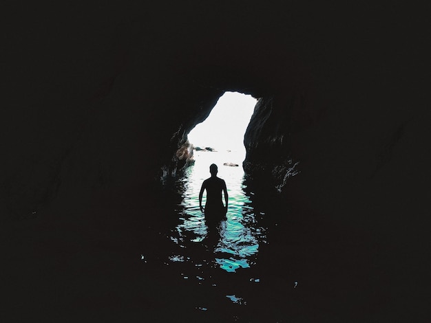 Photo jeune homme rétro-éclairé se baignant dans la grotte