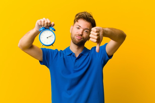 Jeune homme avec un réveil contre orange