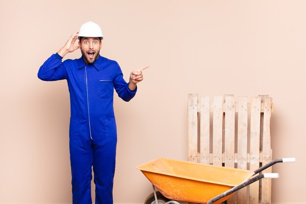 Jeune homme en riant, l'air heureux, positif et surpris, réalisant une excellente idée pointant vers le concept de construction d'espace copie latérale