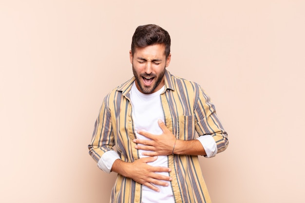 Jeune homme riant aux éclats d'une blague hilarante, se sentant heureux et joyeux, s'amusant
