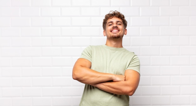 Jeune homme riant joyeusement les bras croisés, avec une pose détendue, positive et satisfaite