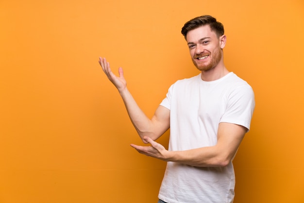 Jeune homme rousse présentant quelque chose