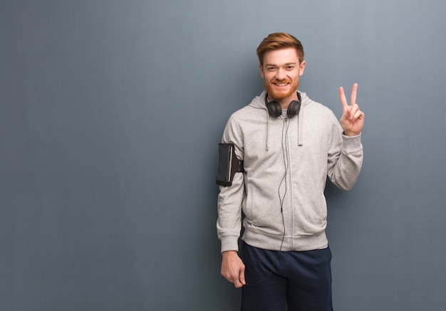 Jeune homme rousse de remise en forme amusant et heureux de faire un geste de victoire