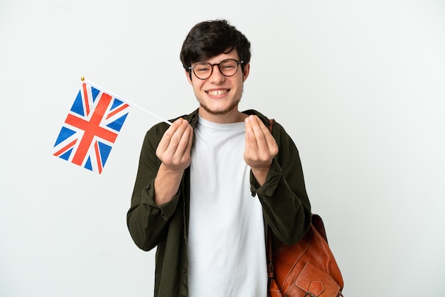 Jeune homme russe tenant un drapeau du Royaume-Uni isolé sur fond blanc faisant un geste d'argent