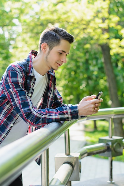 Jeune homme, s'appuyer, balustrade, tenue, smartphone