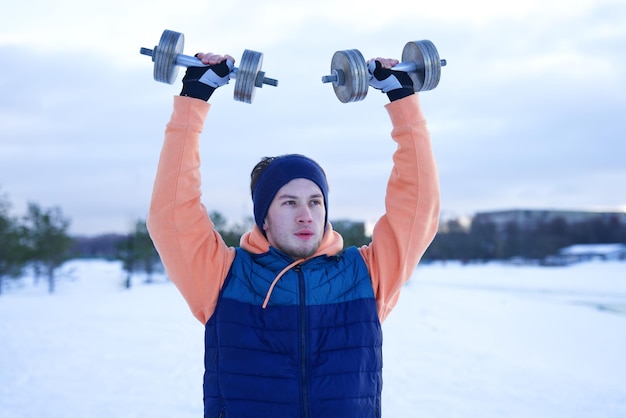 Un jeune homme s'entraîne à l'extérieur par un jour d'hiver froid et enneigé.