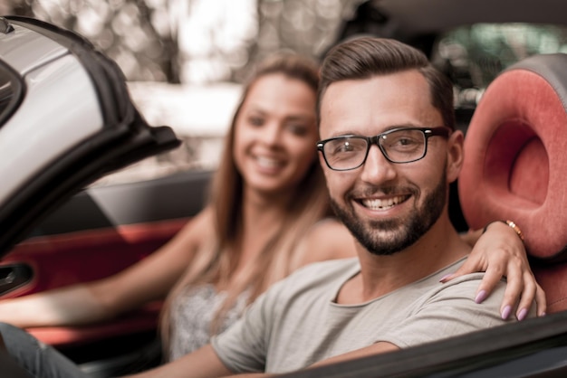 Jeune homme avec sa petite amie à l'intérieur d'une voiture décapotable