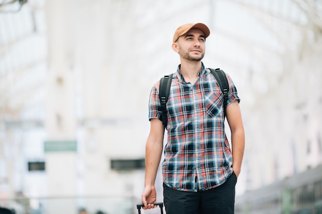 Jeune homme avec sac à dos et valise a raté le train et attend le prochain