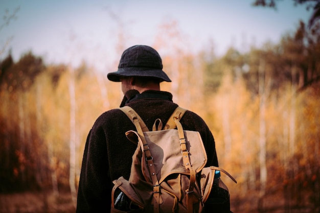 Jeune homme avec un sac à dos vintage dans la forêt.