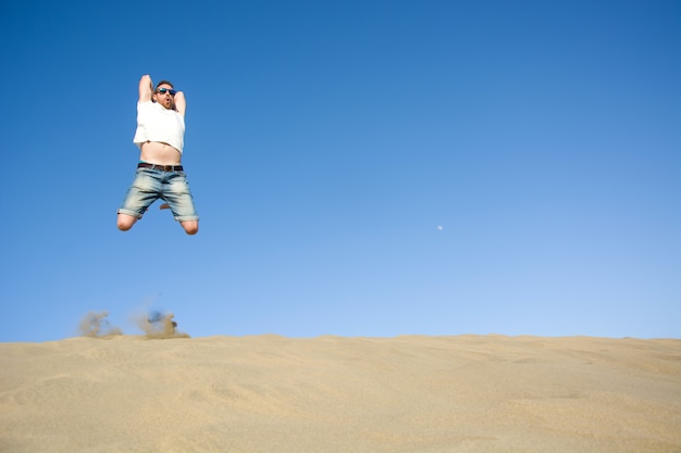 Jeune homme sautant sur une dune