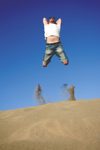 jeune homme sautant sur une dune