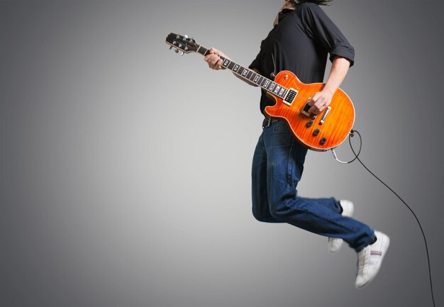 Jeune homme sautant avec guitare