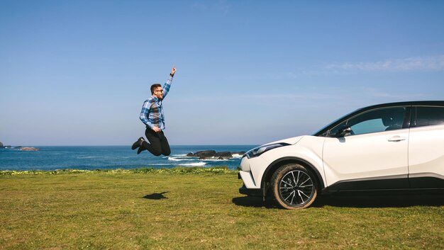 Jeune homme sautant heureux avec la voiture