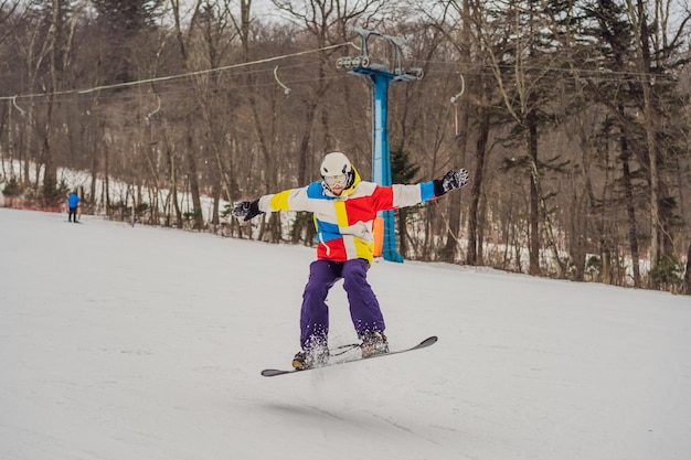 Jeune homme sautant avec un snowboard dans les montagnes