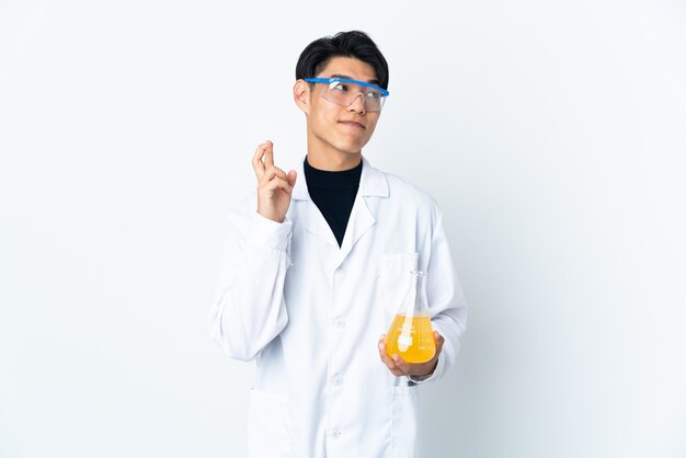 Jeune homme scientifique chinois isolé sur un mur blanc avec des doigts croisés et souhaitant le meilleur